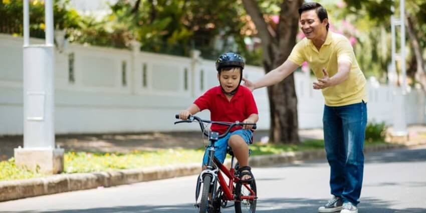 Bé gái đang tập đi xe đạp trẻ em 2 bánh an toàn