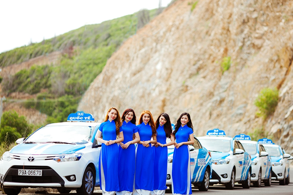 Chiếc xe taxi màu xanh nổi bật di chuyển trên đường phố Ninh Thuận, minh họa cho lựa chọn an toàn khi gọi taxi quốc tế Ninh Thuận.