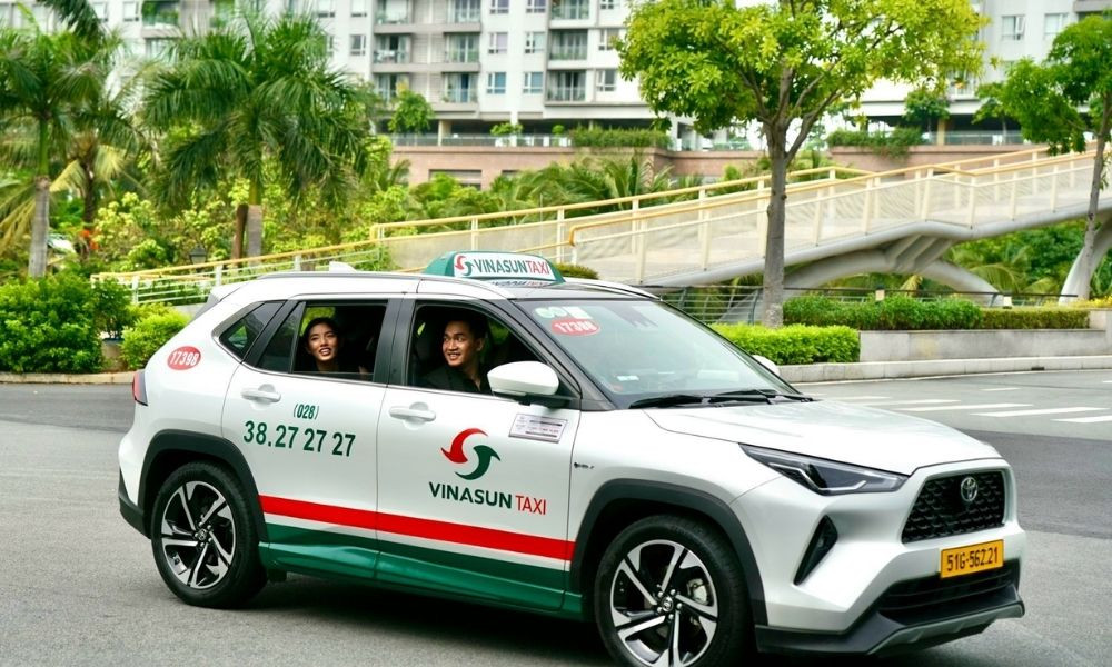 Dàn xe taxi Vinasun màu trắng xanh nổi bật trên phố đông người ở Sài Gòn