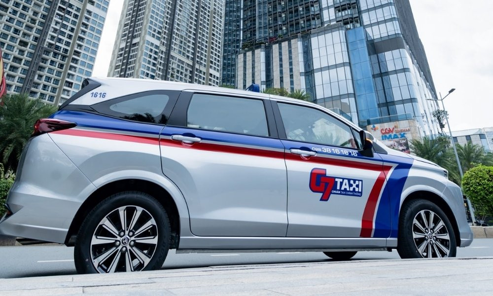 Hàng xe taxi G7 màu trắng đang đỗ trên đường phố Sài Gòn đông đúc
