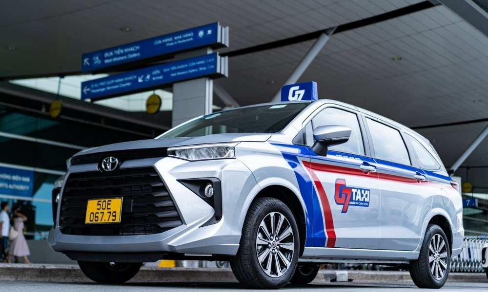 Hàng xe taxi G7 màu trắng với logo đỏ trên đường phố Sài Gòn