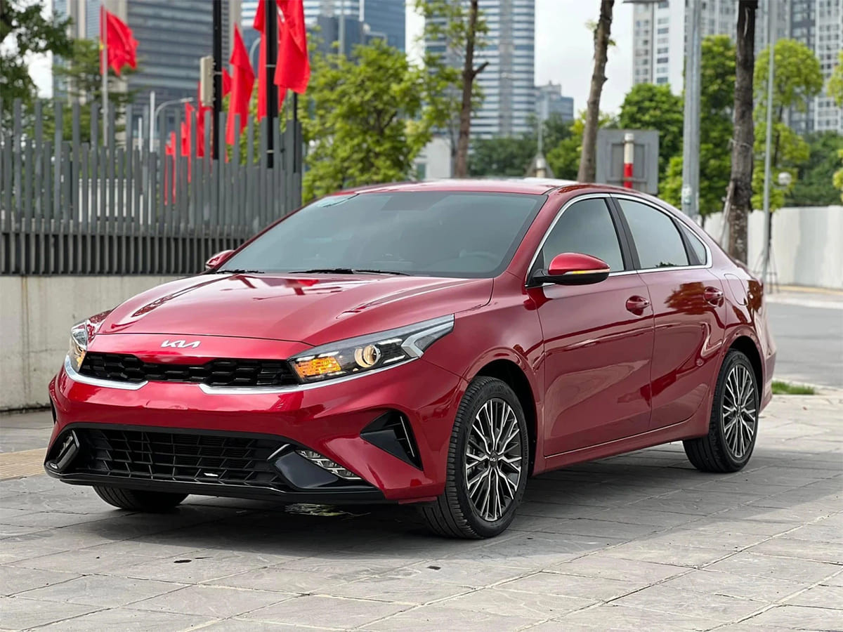 Hình ảnh xe ô tô Kia K3 màu trắng đang di chuyển trên đường, thể hiện sự an toàn cần có bảo hiểm
