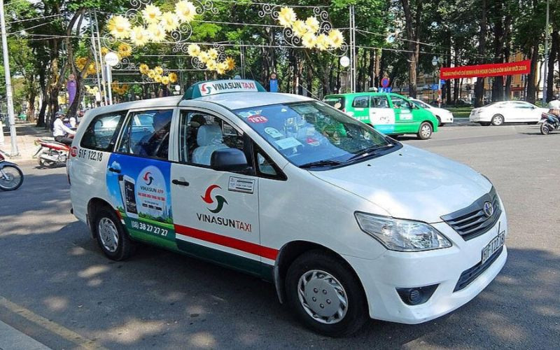 Một chiếc taxi Vinasun màu trắng xanh đỗ trên đường phố Hà Nội, sẵn sàng phục vụ khách hàng.