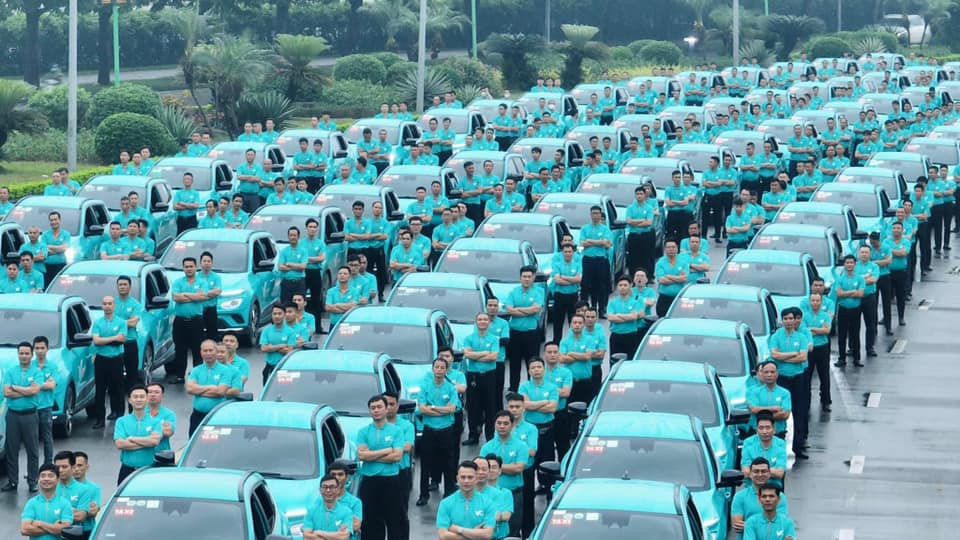 Một chiếc taxi VinFast Thanh Hoá (Xanh SM) đang di chuyển trên đường phố đông đúc, thể hiện sự năng động của dịch vụ taxi xanh Thanh Hoá.