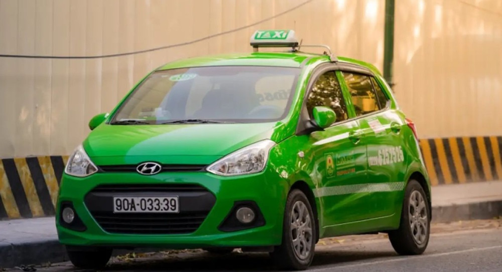 Một chiếc xe Taxi Mai Linh màu xanh lá cây quen thuộc đang di chuyển trên đường, biểu tượng của sự tiện lợi và phổ biến