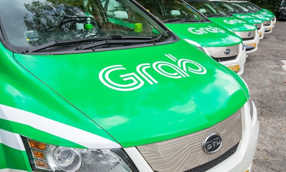 Một người đang sử dụng điện thoại để đặt xe qua ứng dụng Grab, với logo Grab hiển thị