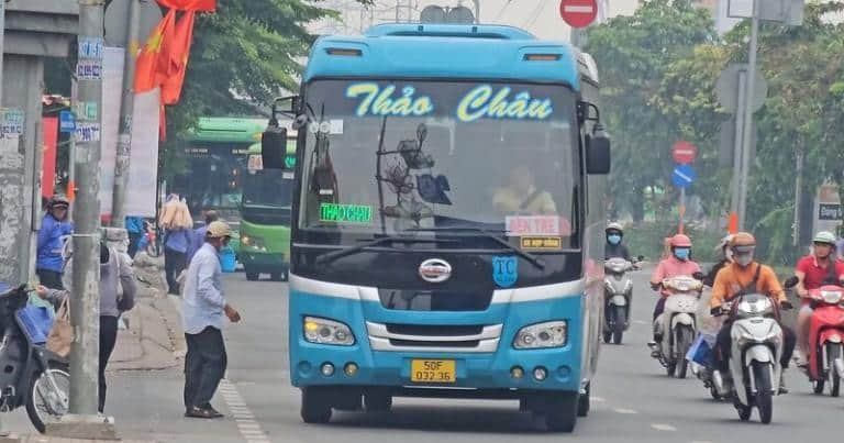 Người đàn ông đứng cạnh xe khách Thảo Châu màu xanh