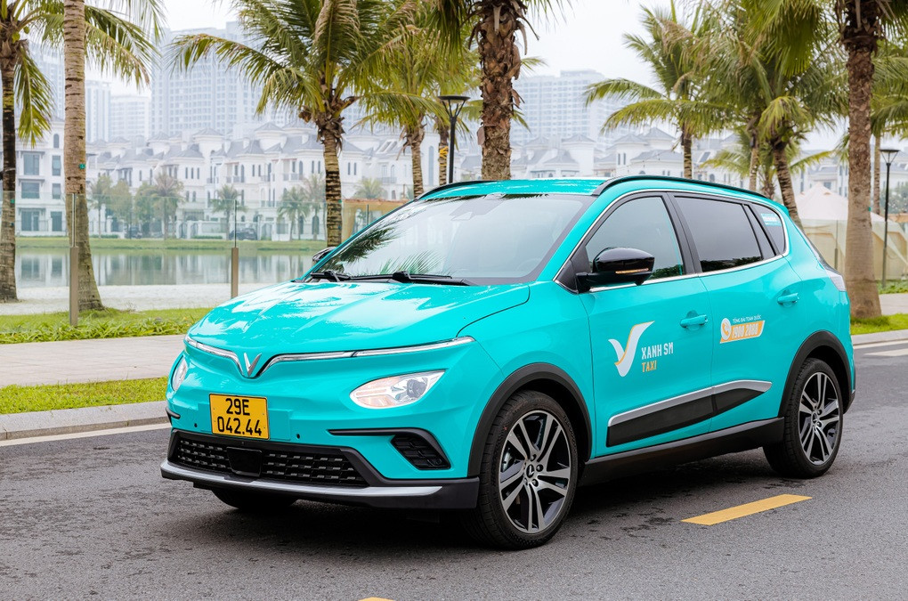 Người dân vẫy gọi xe taxi điện Xanh SM màu xanh cyan trên đường phố, một trong các phương thức đặt xe