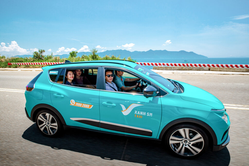 Nữ tài xế taxi điện VinFast VF e34 thân thiện mở cửa đón khách tại Nha Trang