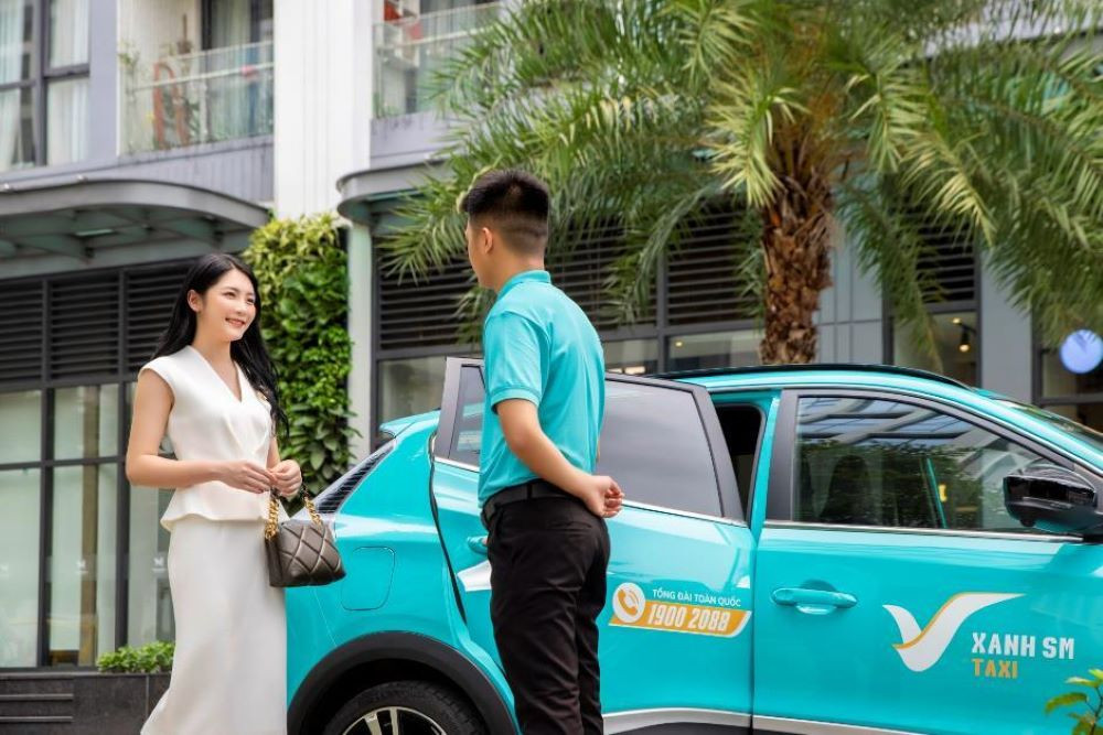 Tài xế taxi điện Xanh SM đang nở nụ cười bên chiếc xe VinFast, biểu tượng cho trải nghiệm di chuyển êm ái và dịch vụ chuyên nghiệp của taxi xanh Việt Trì.
