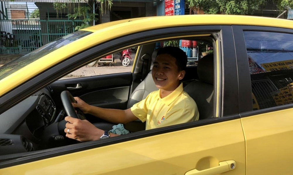 Tài xế Vina Taxi đang tươi cười chào đón khách hàng, tạo không khí thân thiện