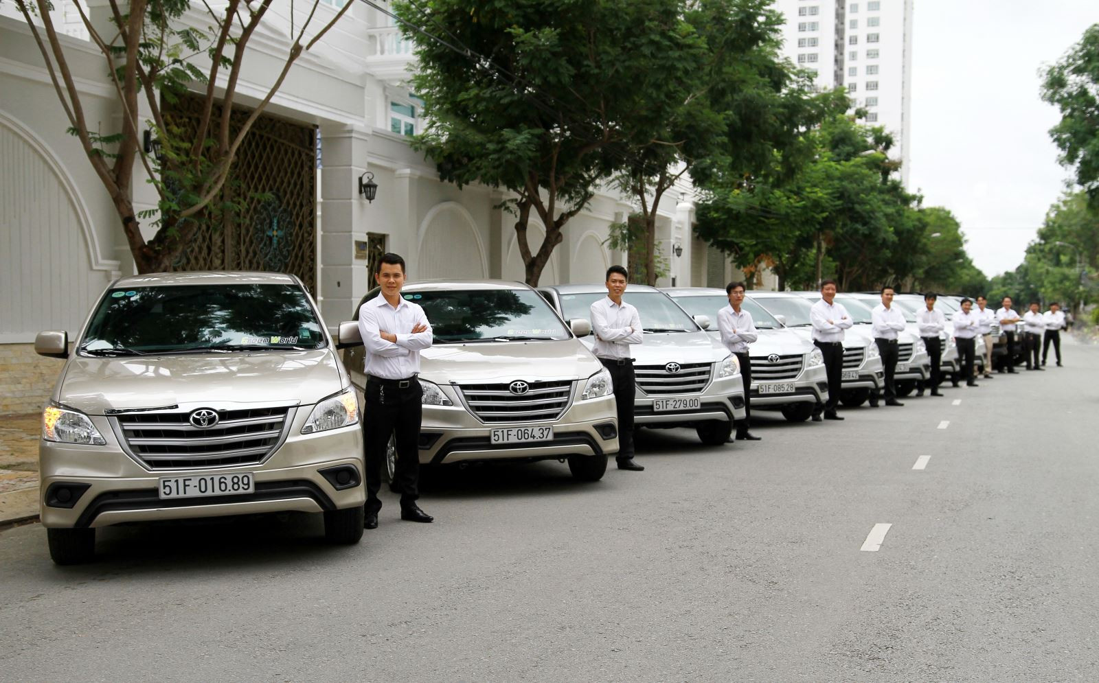 xe taxi 7 chỗ màu trắng đỗ cạnh hàng cây