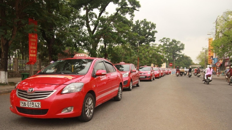 Xe taxi Hương Giang màu xanh dương đỗ cạnh bờ sông Hương