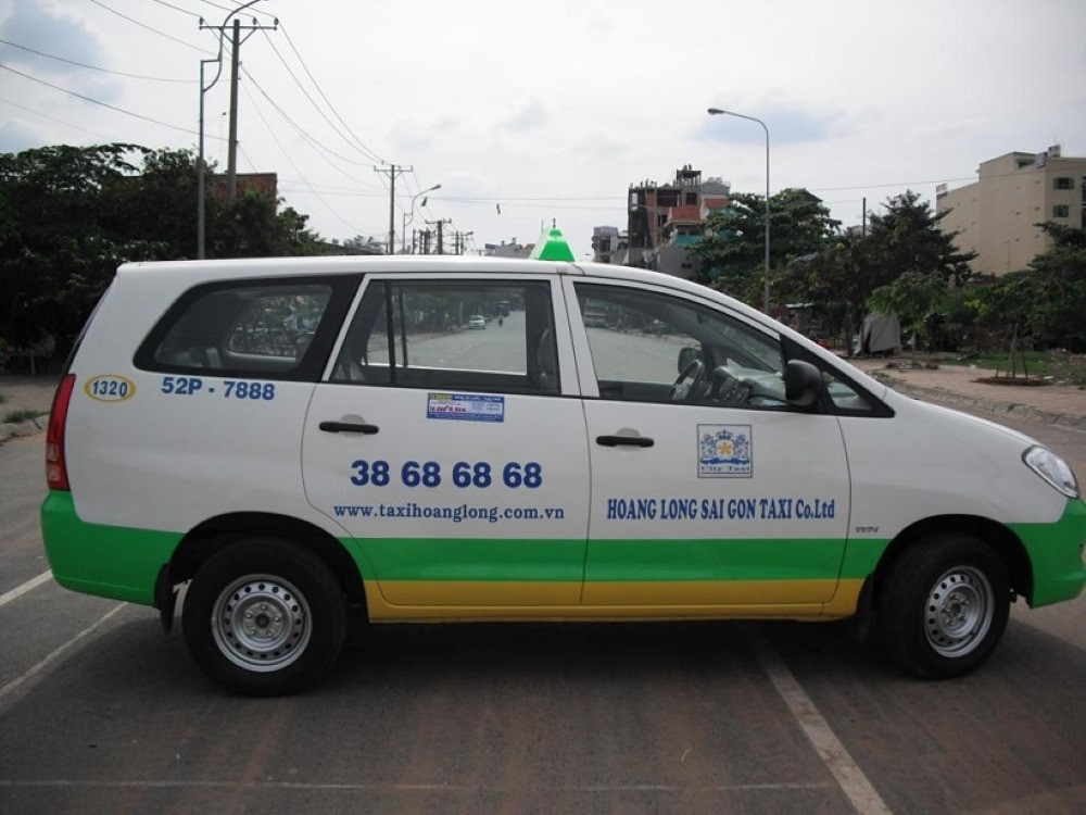 Xe taxi Sài Gòn Hoàng Long màu xanh lá cây trên đường phố đông đúc