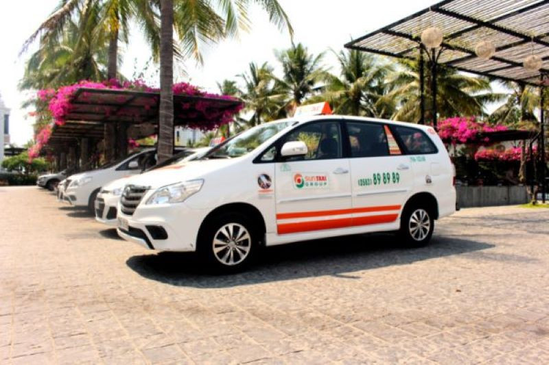 Xe taxi Sun Taxi màu trắng đang chờ khách trước một tòa nhà, thể hiện dịch vụ taxi Quảng Ngãi