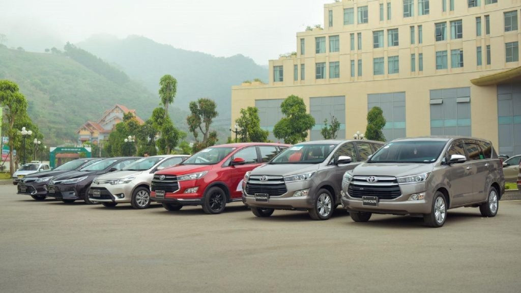 Xe taxi Toyota màu trắng đang chạy trên đường tại Hồ Tràm Xuyên Mộc