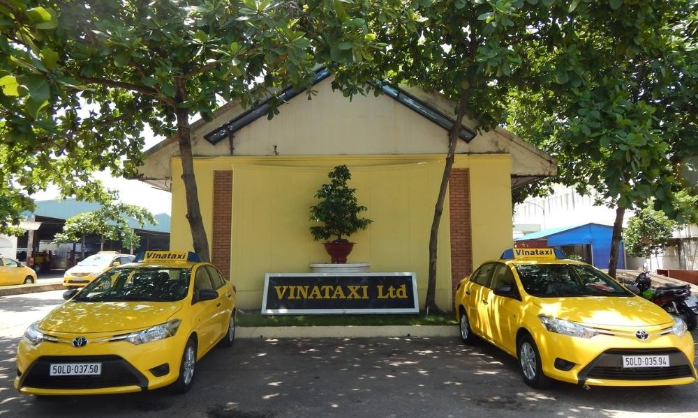 Xe taxi Vina Taxi màu vàng nổi bật đang chờ khách trên một con đường Sài Gòn